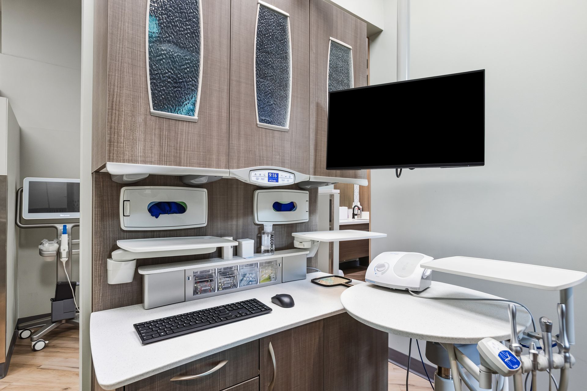 Dental office workspace with monitor, computer, and dental equipment.