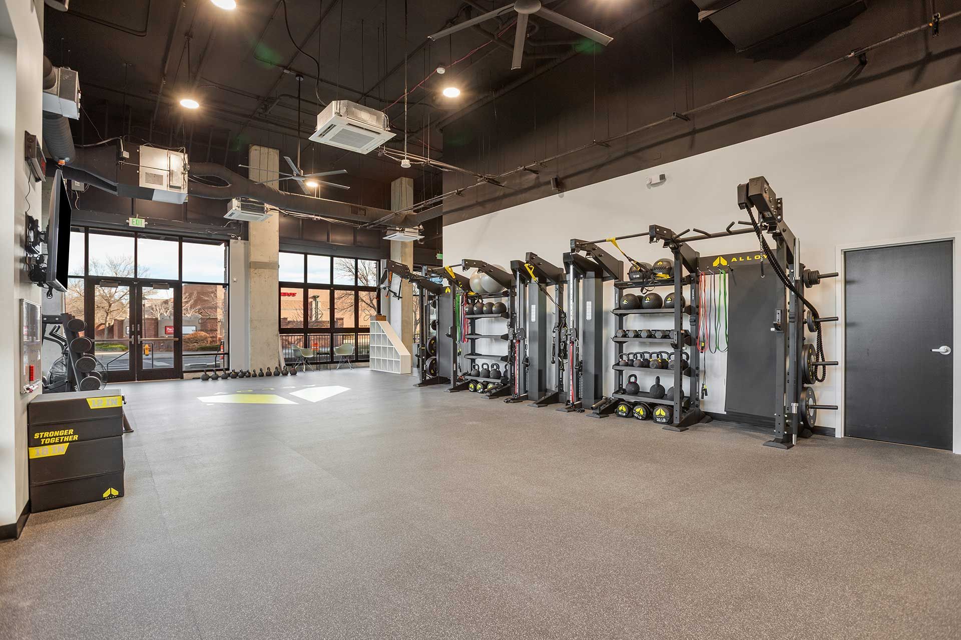 gym interior with exercise equipment against a white wall and large windows