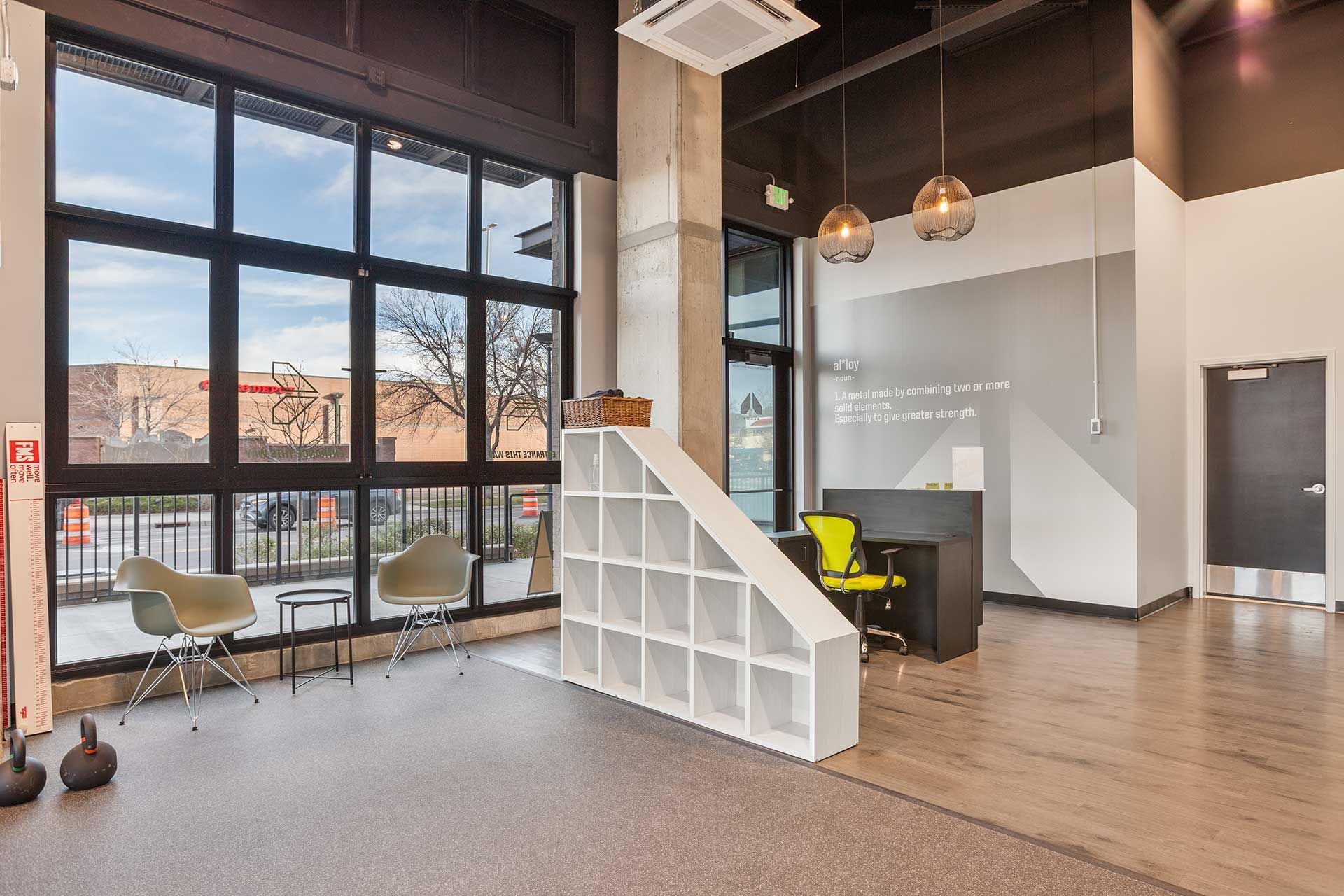 modern gym entrance with large windows, seating, reception desk, and decorative shelving