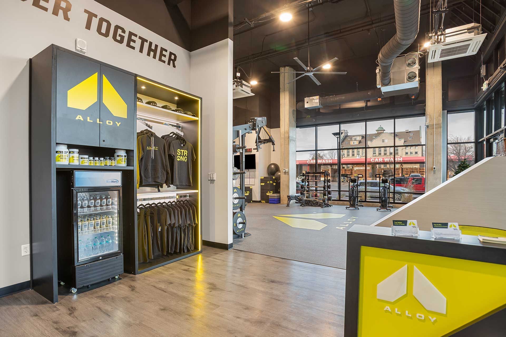 interior of a gym with exercise equipment, storage cabinets with logo and apparel are on the left
