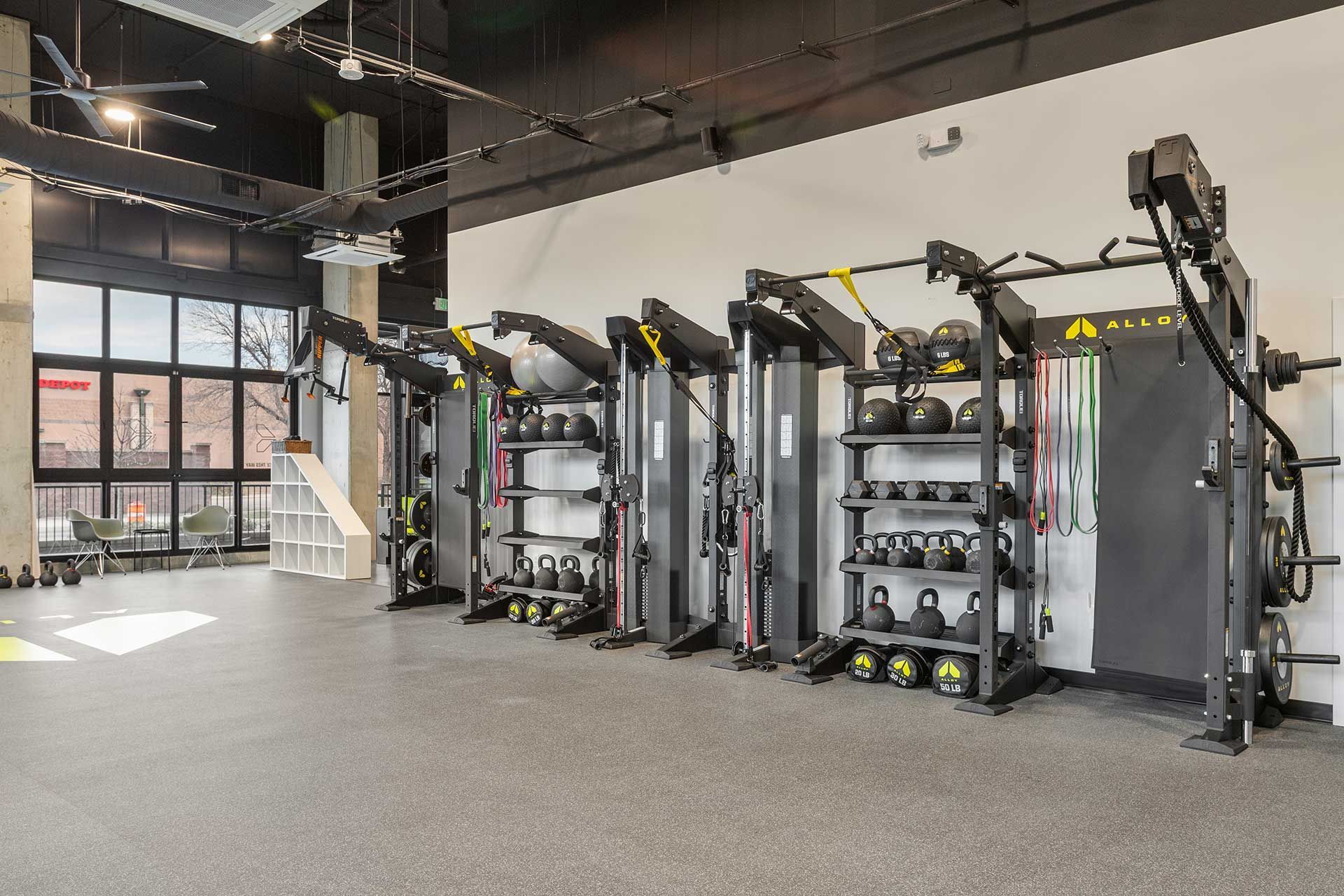 gym with exercise equipment, including weight machines, kettlebells, and resistance bands, arranged in a row