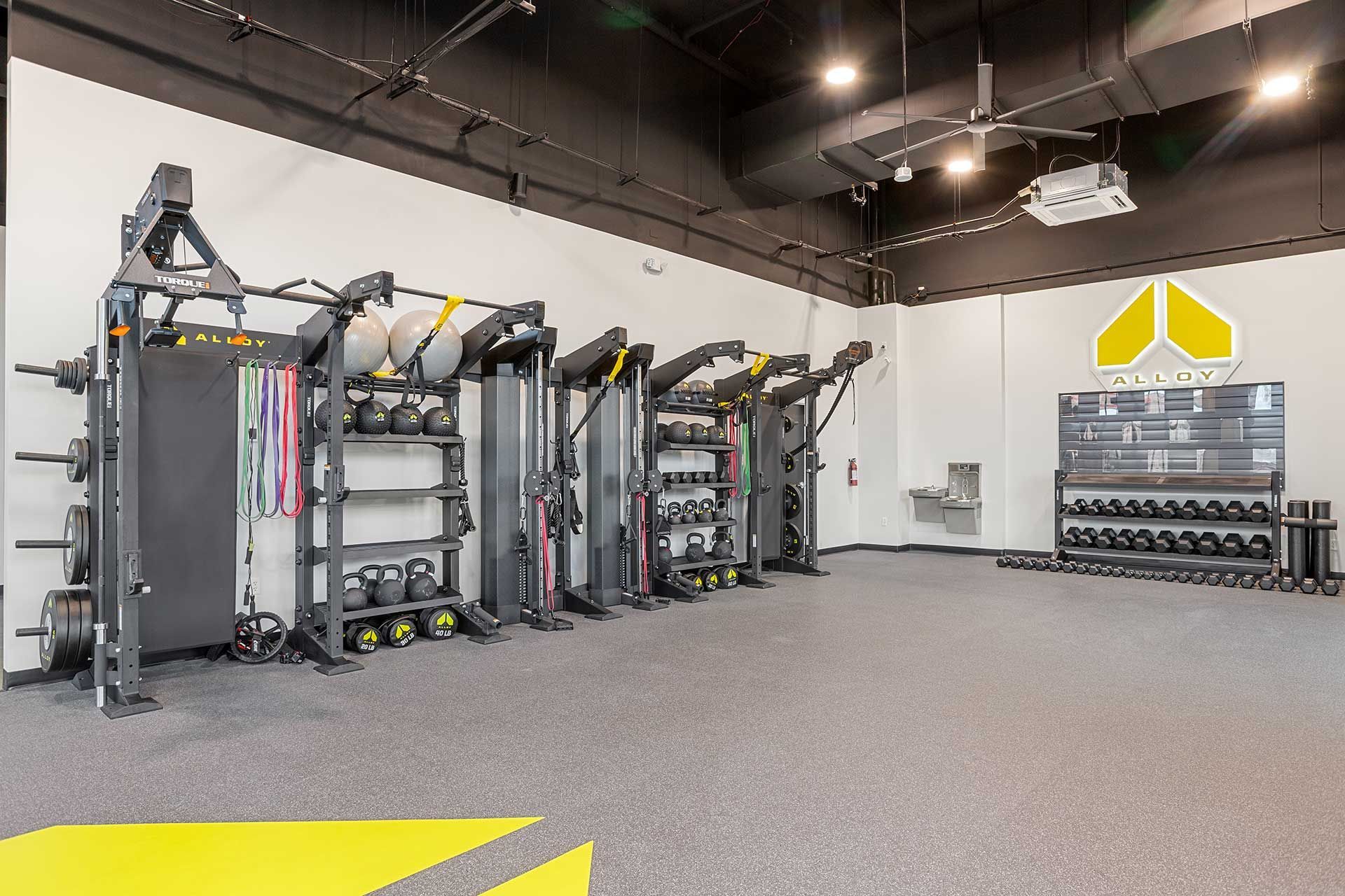 gym interior with weight machines, dumbbells, and storage racks on a gray floor
