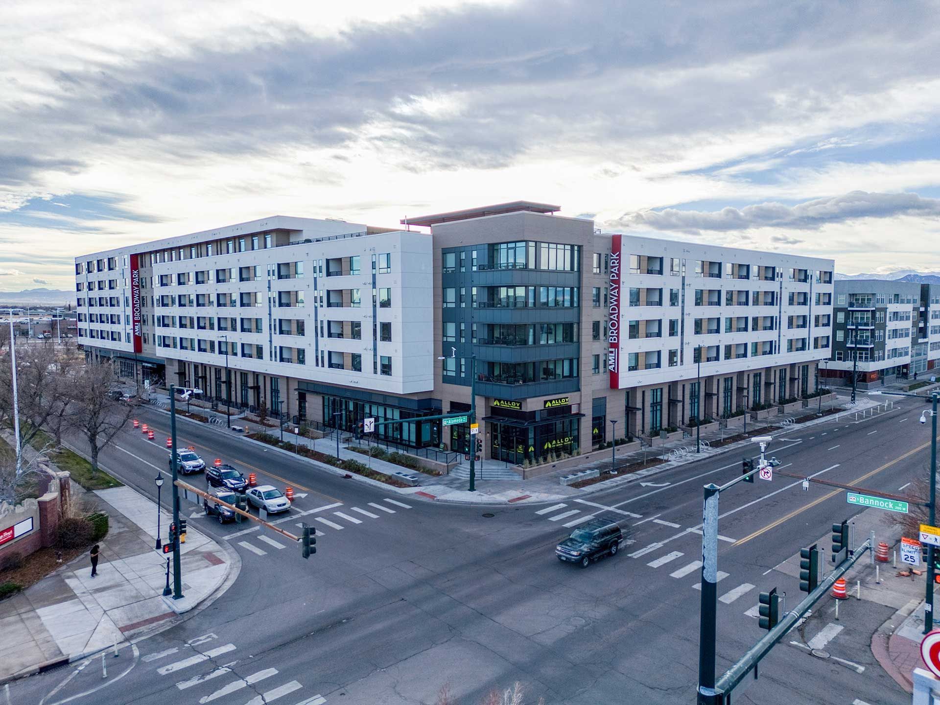 modern apartment building on a city corner with street traffic and cloudy sky