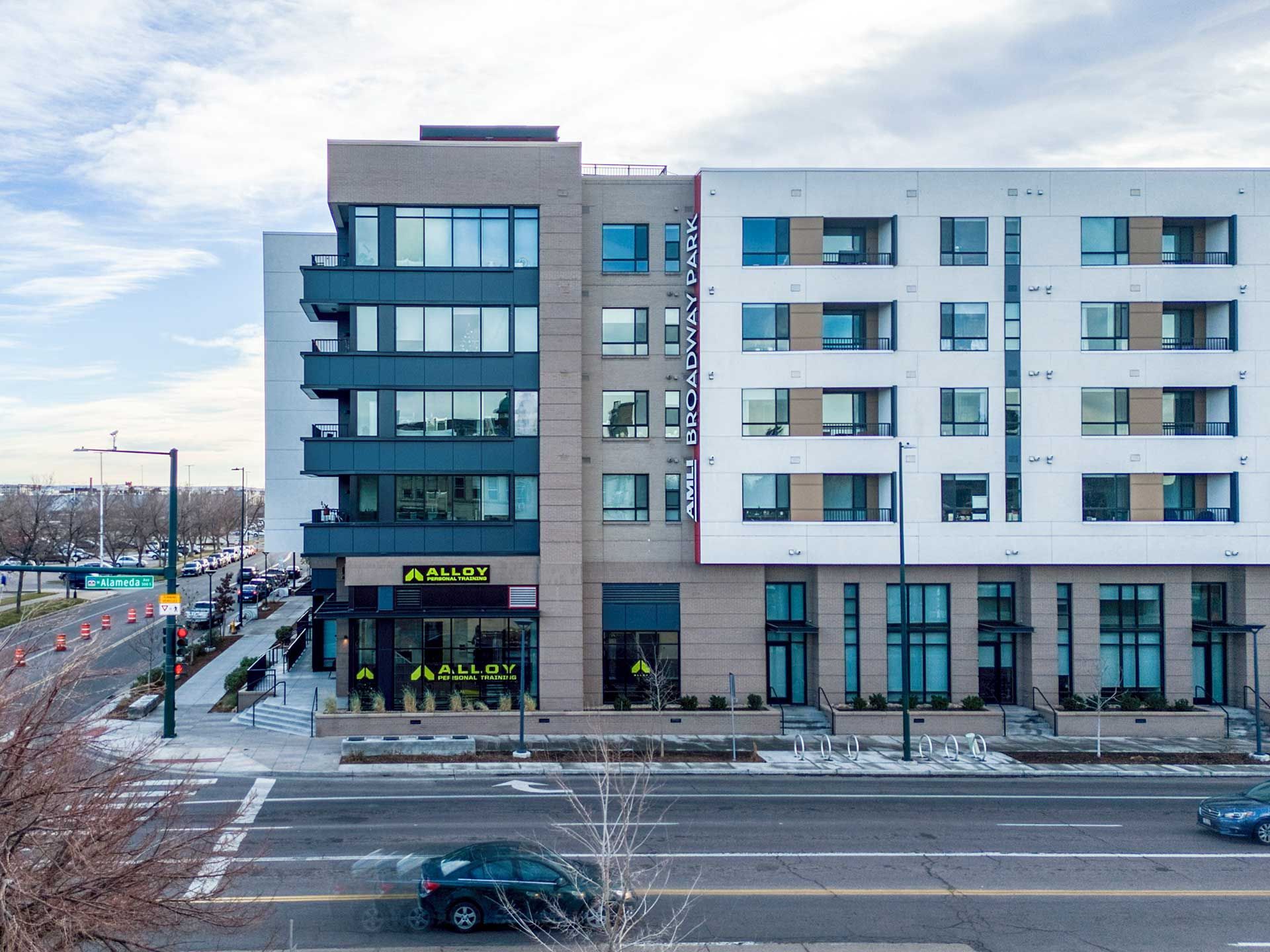 modern multi-story building with a gym on the ground floor next to a road