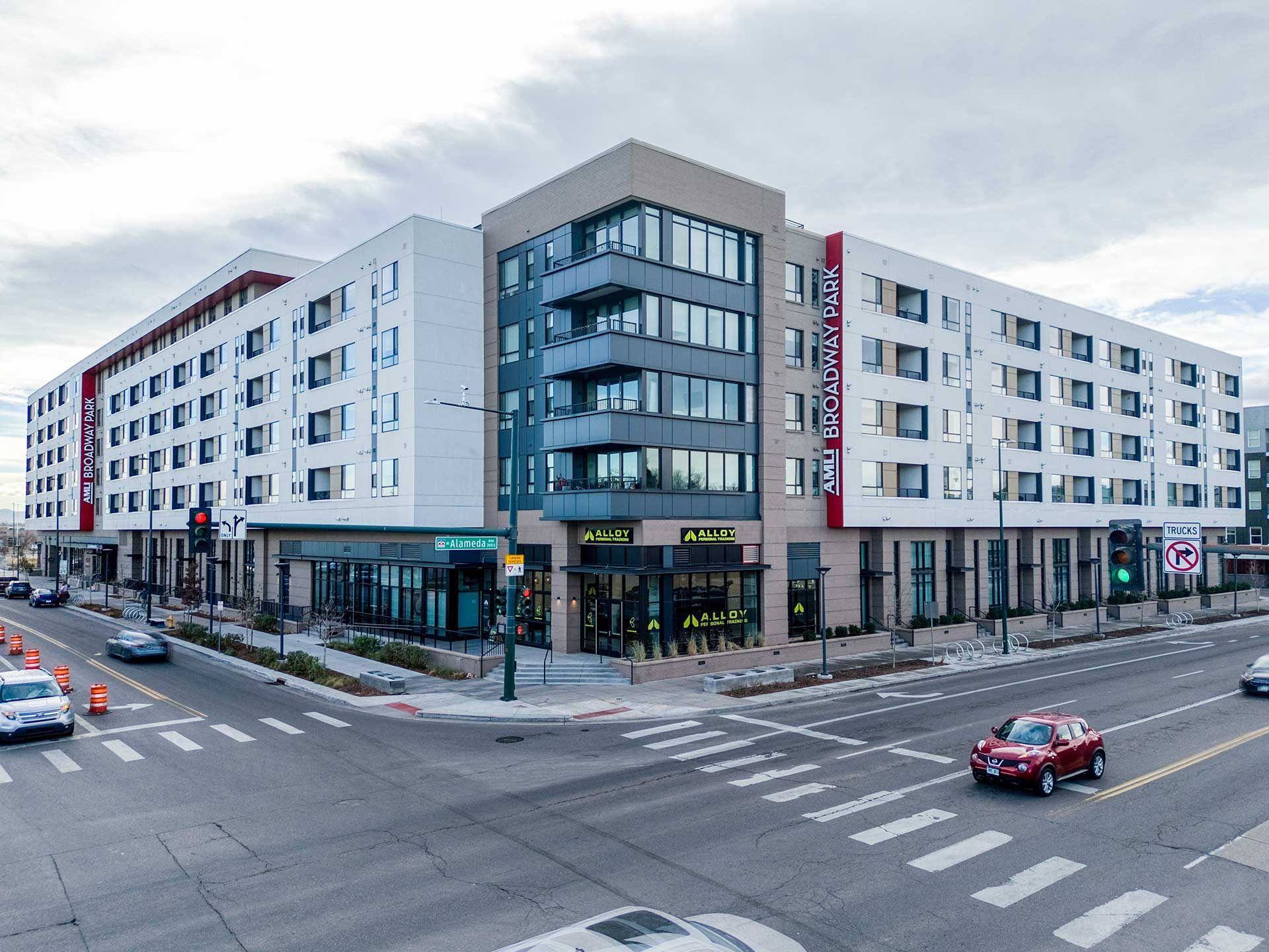 modern multi-story building at a street corner, with a gym on the ground floor and residential units above