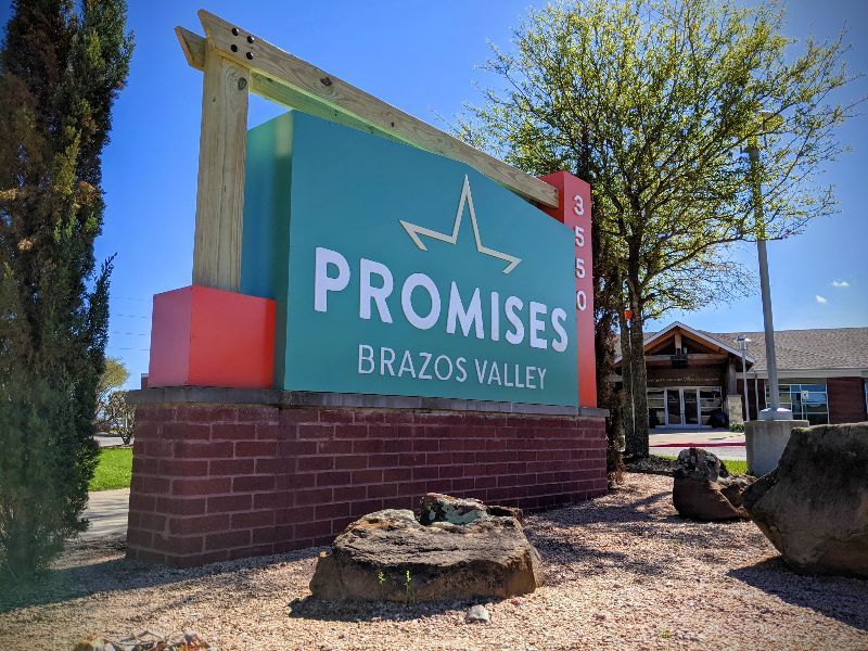 A green and red sign for promises brazos valley
