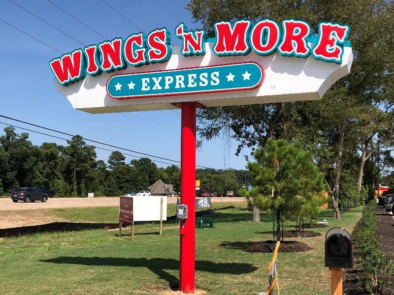 A red and white sign for wings n more express