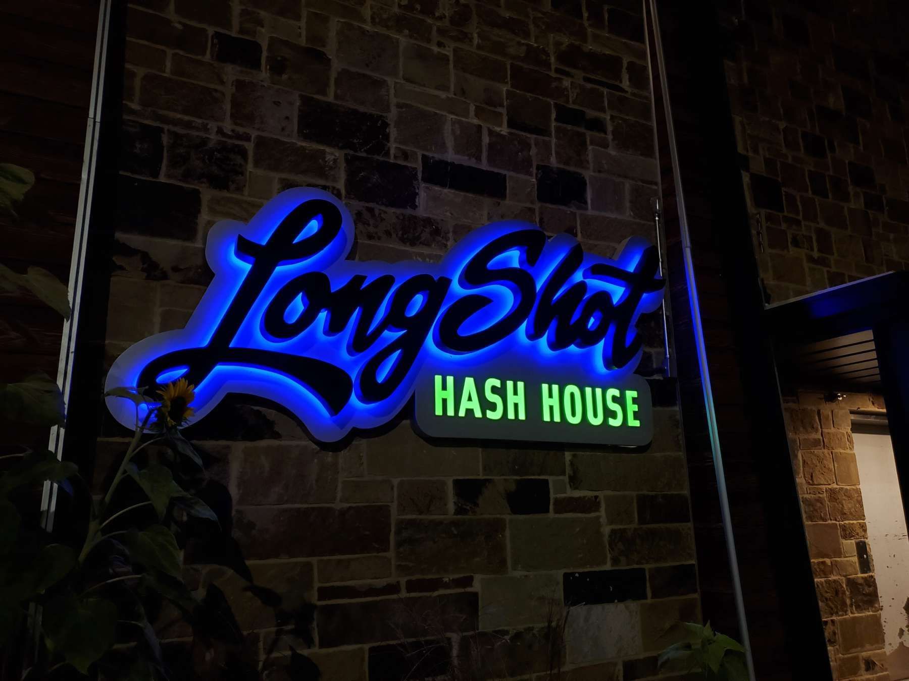 A long shot hash house sign is lit up at night