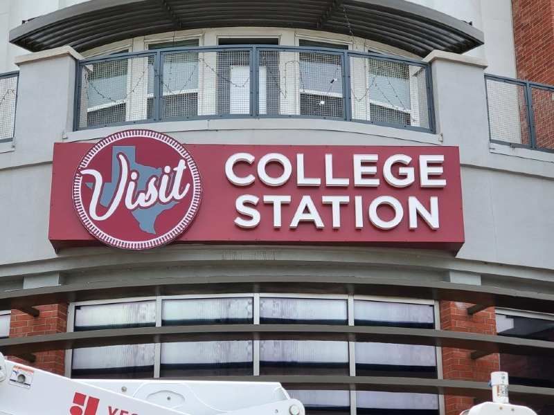 A red sign that says visit college station on it