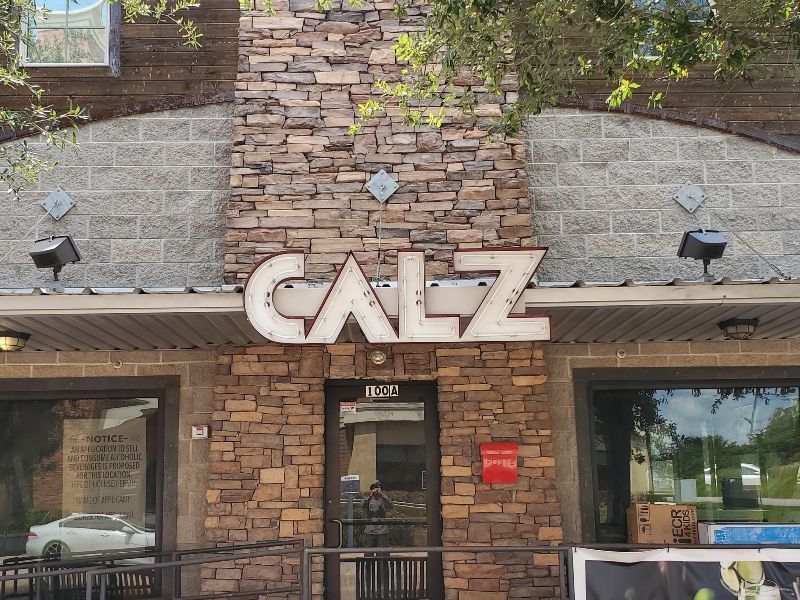 A brick building with a sign that says calz on it.
