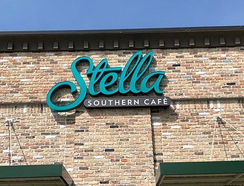 A stella southern cafe sign is on a brick building.