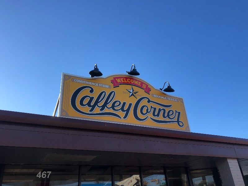 A yellow sign on top of a building that says calley corner