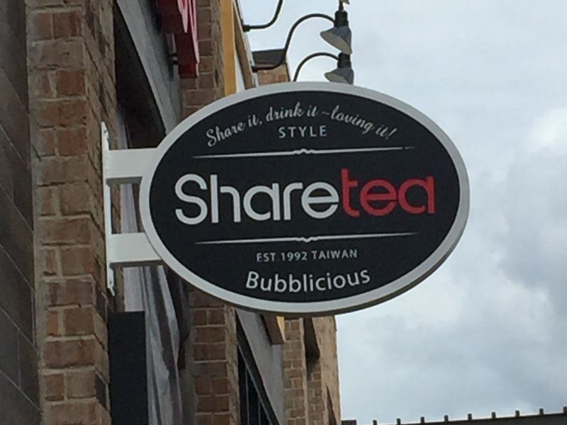 A sign on the side of a building that says share tea