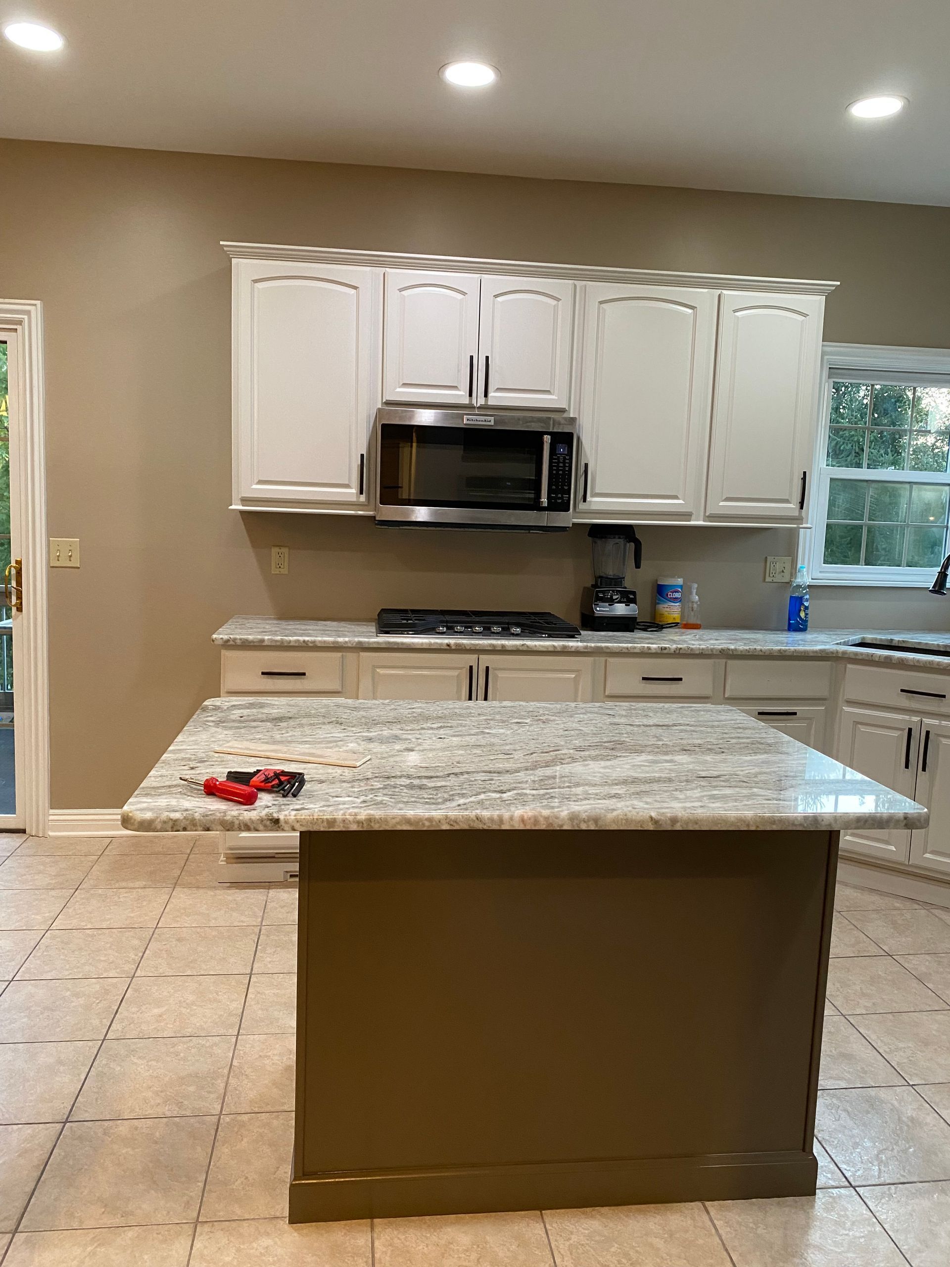 a kitchen with wood cabinets and a marble countertop (After)