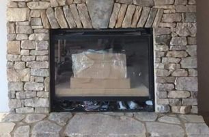 A stone fireplace with a glass door in a living room