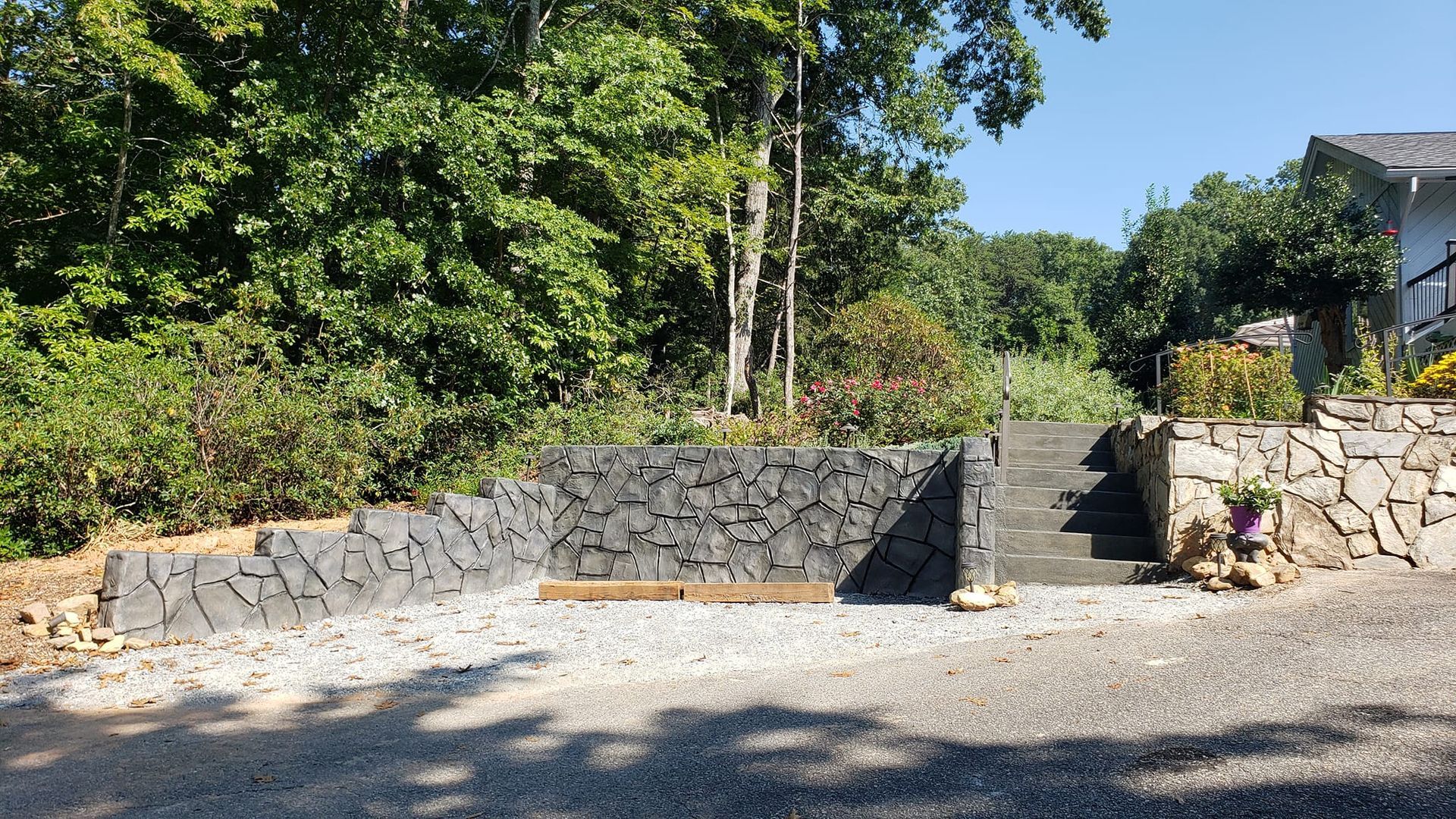 A stone wall with stairs leading up to a house surrounded by trees