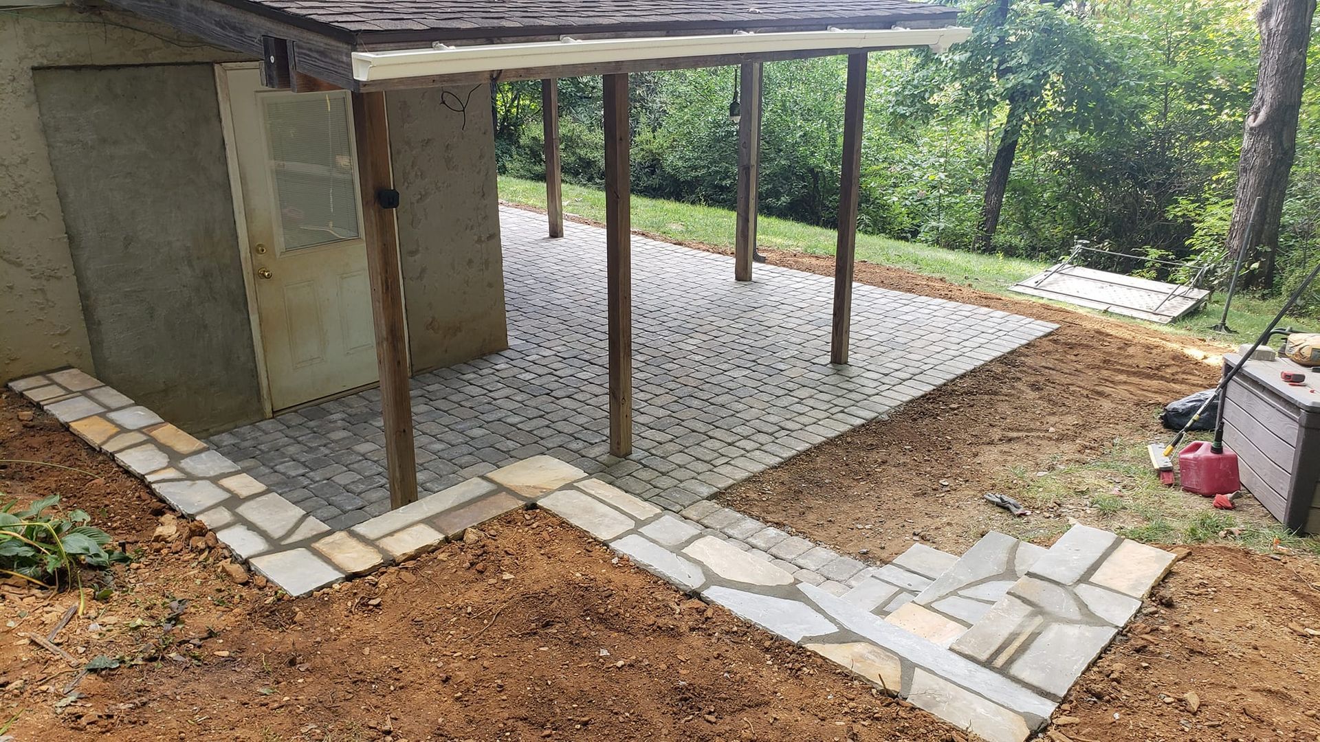 A stone walkway leading to a shed with a wooden roof