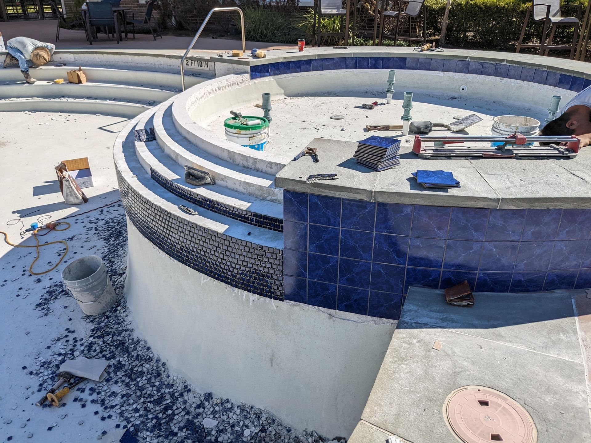 A man is working on a swimming pool with blue tiles.