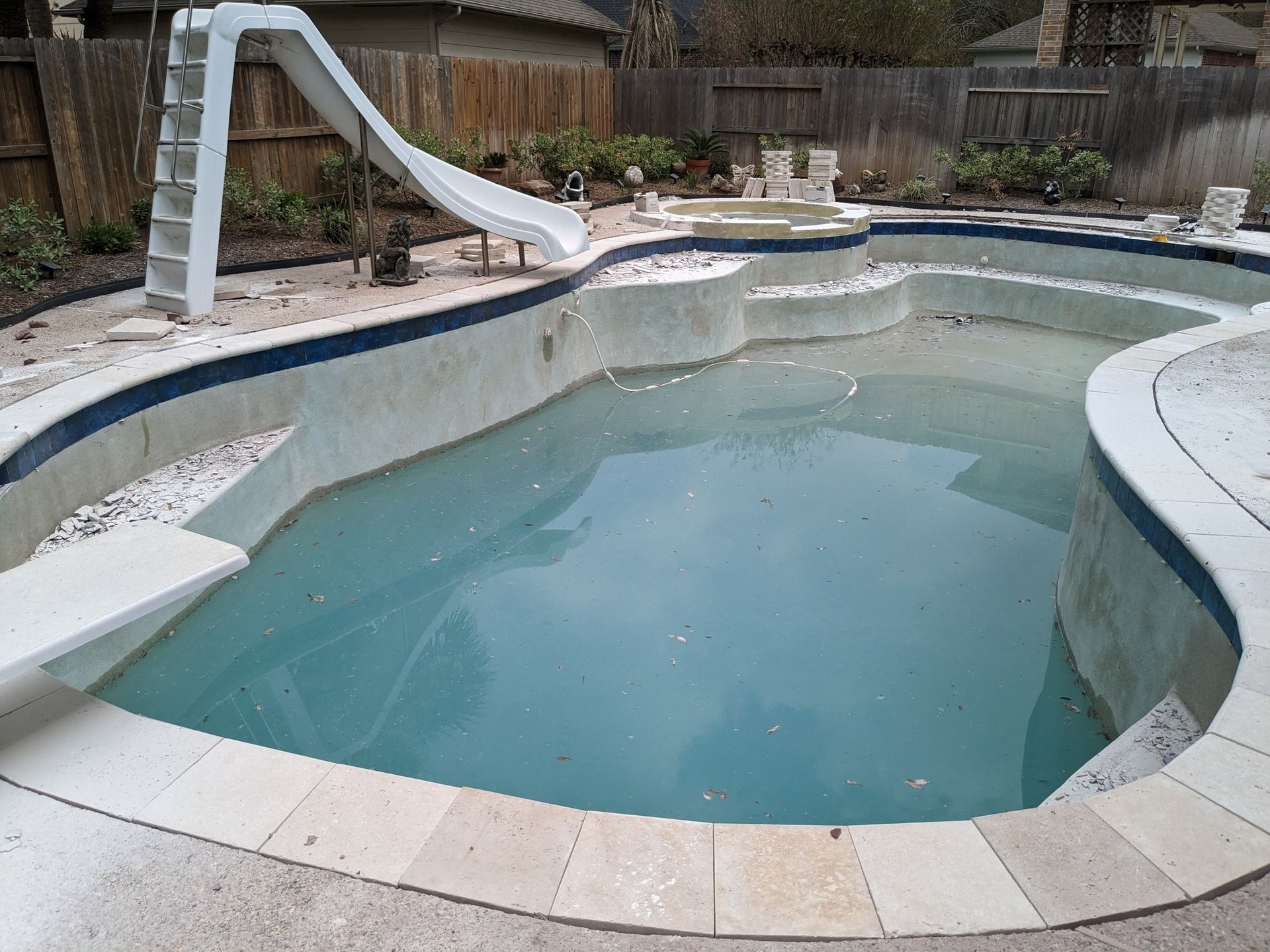 A large swimming pool with a slide in the backyard