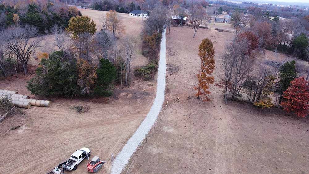 An aerial view of a truck pulling a trailer down a dirt road.