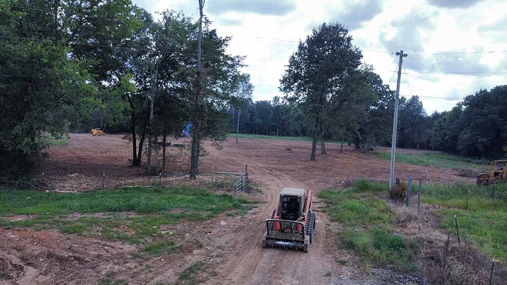 A bulldozer is driving down a dirt road in a field.