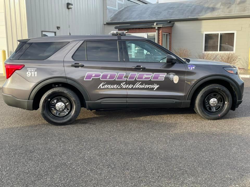 Gray Kansas State University Police SUV with black wheels parked outside a building.