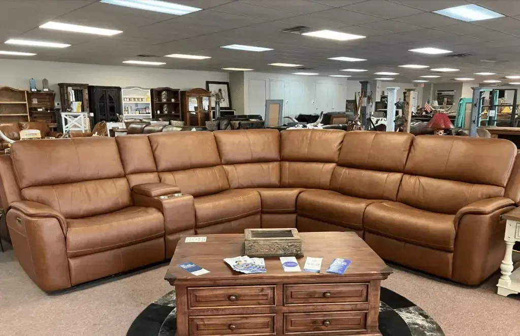 Brown leather sectional sofa in a furniture store showroom with a wooden coffee table.