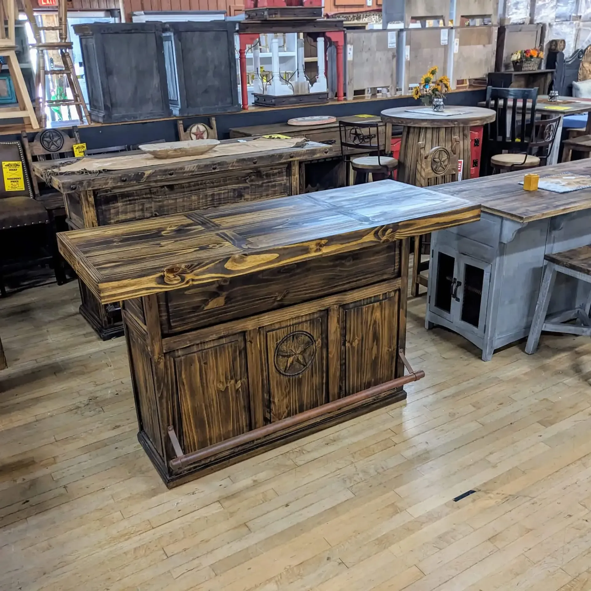 Wooden bars for sale in a warehouse. Various sizes, styles, and finishes, including a bar with copper foot rail.