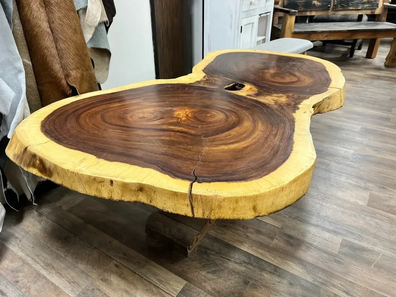 Live edge wood coffee table, brown and tan, in a wood shop.