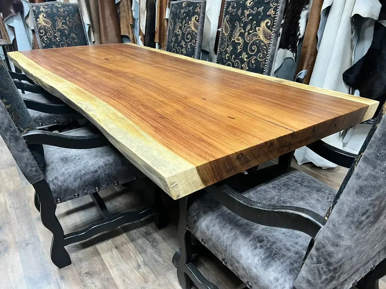 Wooden table with live edge and chairs with gray and black patterned upholstery.