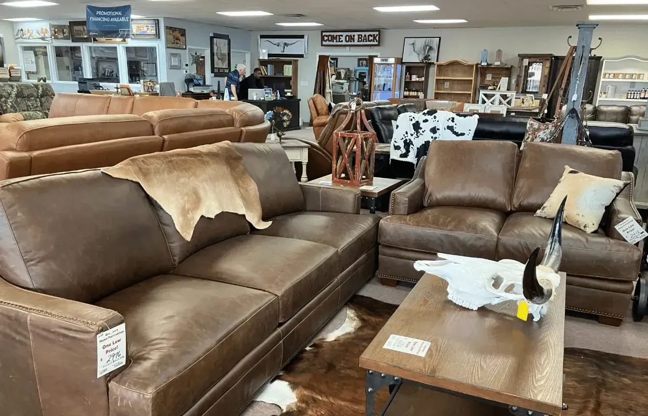 Leather furniture showroom with sofas, chairs, and tables on display.