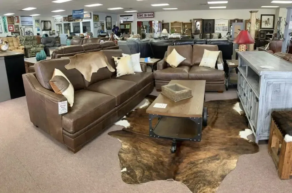 Furniture showroom with leather sofas, coffee table, rug, and other furniture.