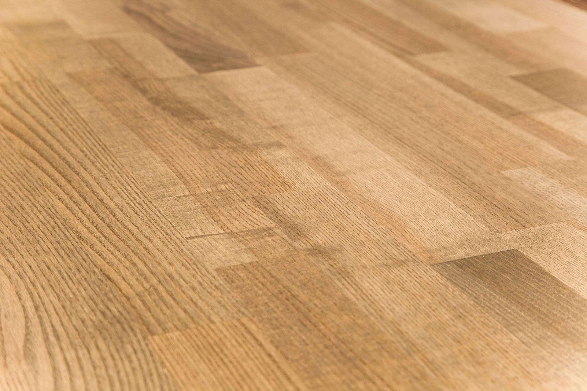 A close-up of a light brown, wooden butcher block surface with visible grain patterns and rectangular plank joints.