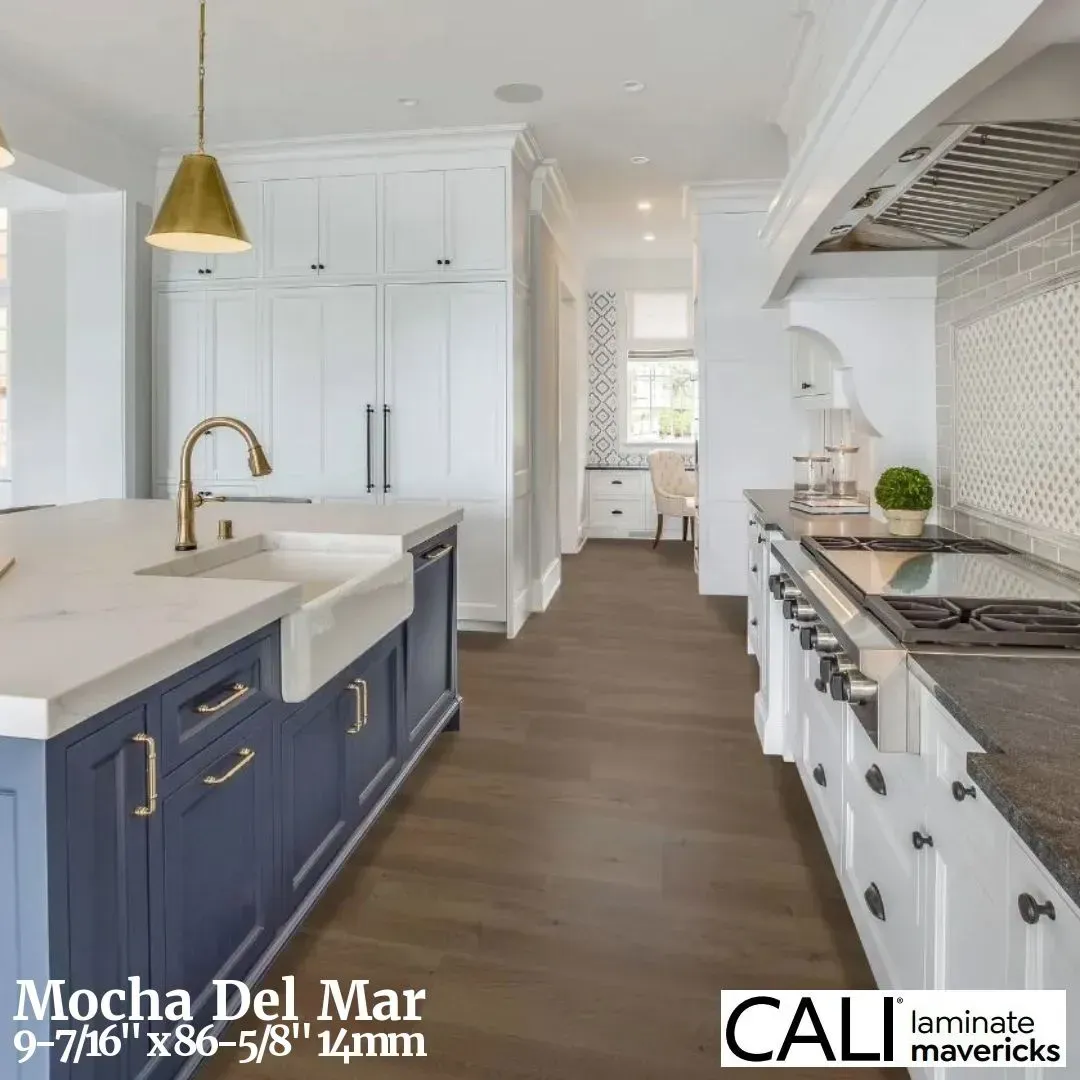 A kitchen with blue island cabinets, white perimeter cabinets, light stone countertops, and brown wood-look flooring.