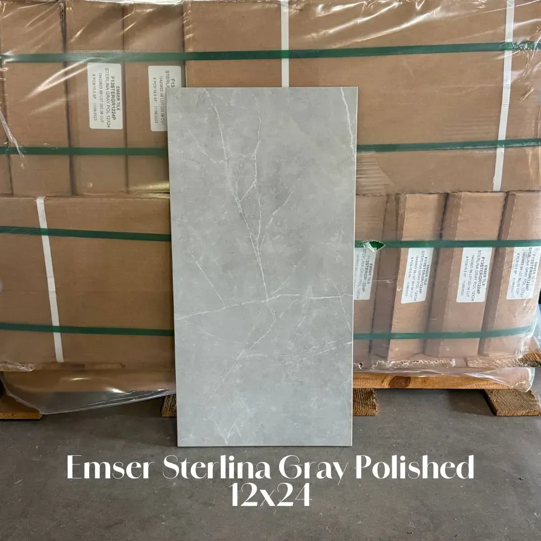 A single light gray polished marble-look tile stands in front of stacked, shrink-wrapped boxes on a wooden pallet.