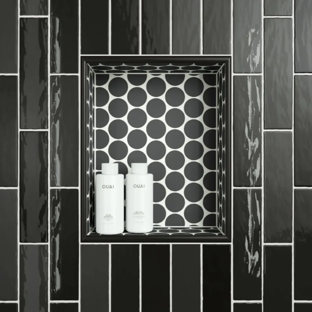 A shower wall with glossy black vertical tiles and a rectangular recessed niche featuring a white-and-black circle pattern.