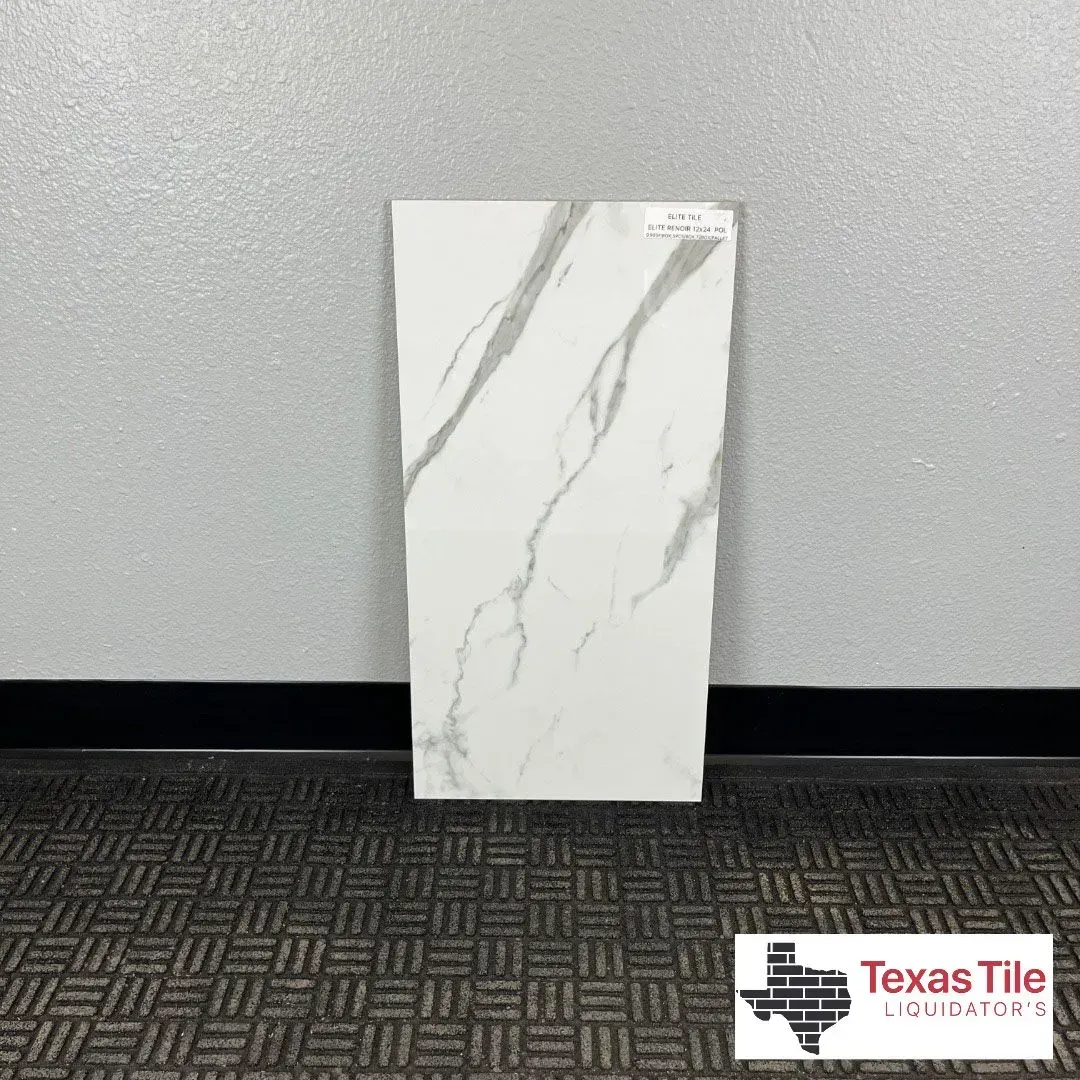 A vertical white rectangular tile with grey marble veining, standing against a grey wall above a textured floor.