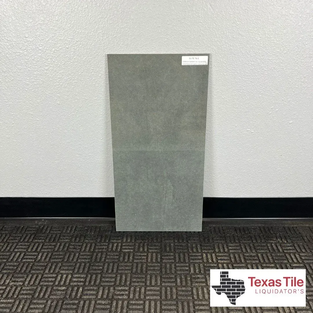 A rectangular, matte-gray tile standing upright against a white wall with a Texas Tile Liquidators logo in the corner.