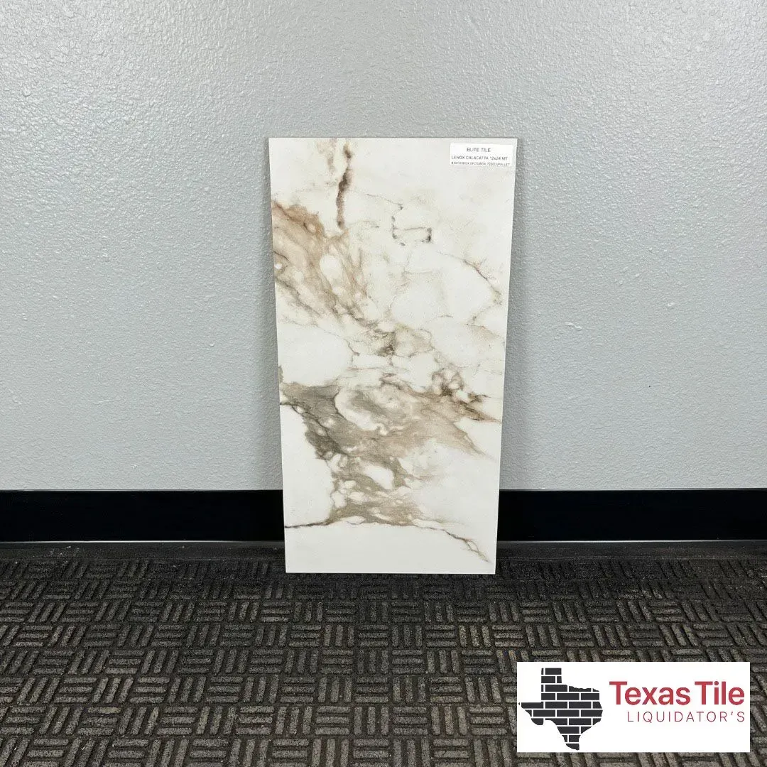A rectangular marble-look tile sample with white and tan veining, standing upright against a grey wall.