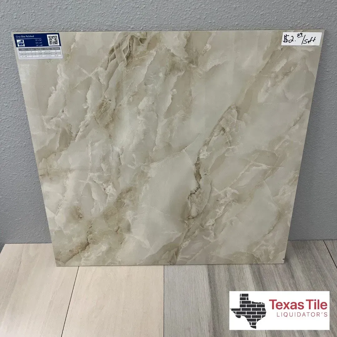 A cream and beige marble-patterned floor tile displayed on a showroom shelf with the Texas Tile Liquidators logo.