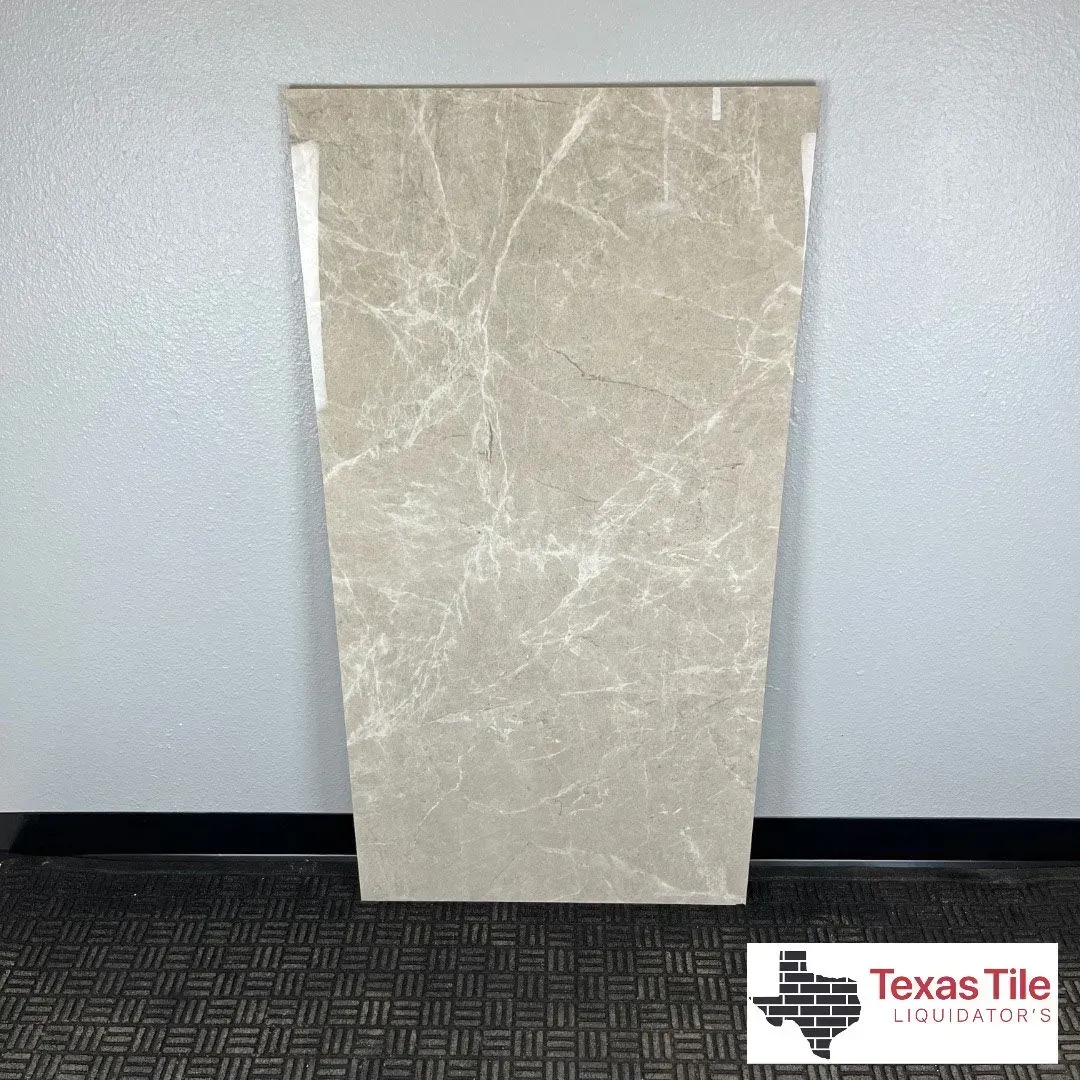 A rectangular, light beige porcelain tile with white marble-like veining patterns displayed in a store.