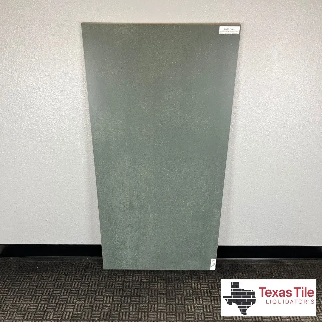 A rectangular, dark green tile with a subtle, textured stone-like finish stands against a light wall.