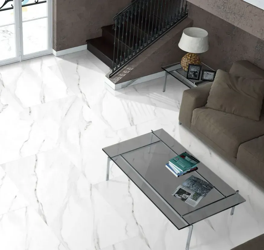 A high-angle view of a living room with white marble floors, a brown sofa, a glass coffee table, and a staircase.