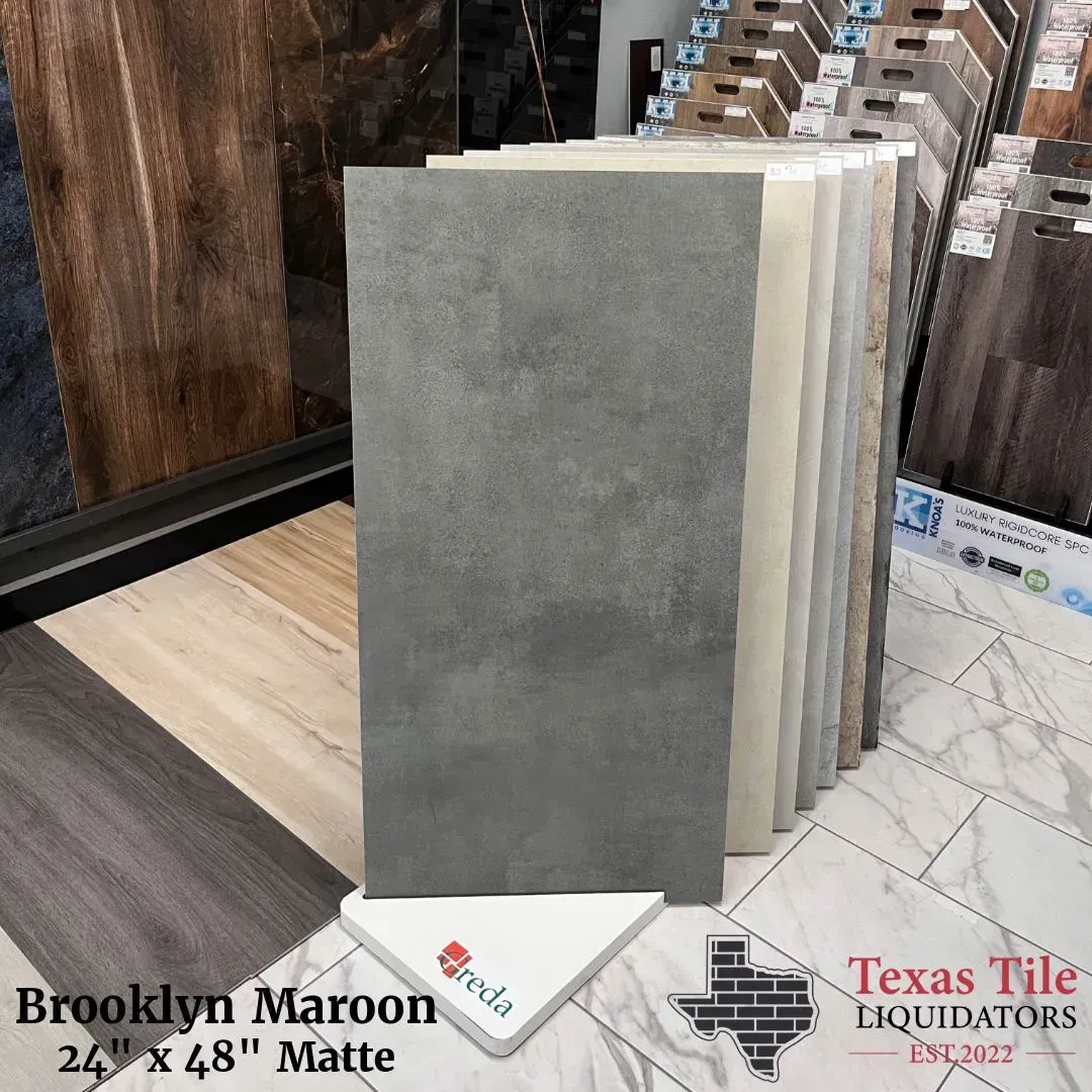 Display rack of rectangular tile samples in varying neutral tones, with Brooklyn Maroon flooring in the background.