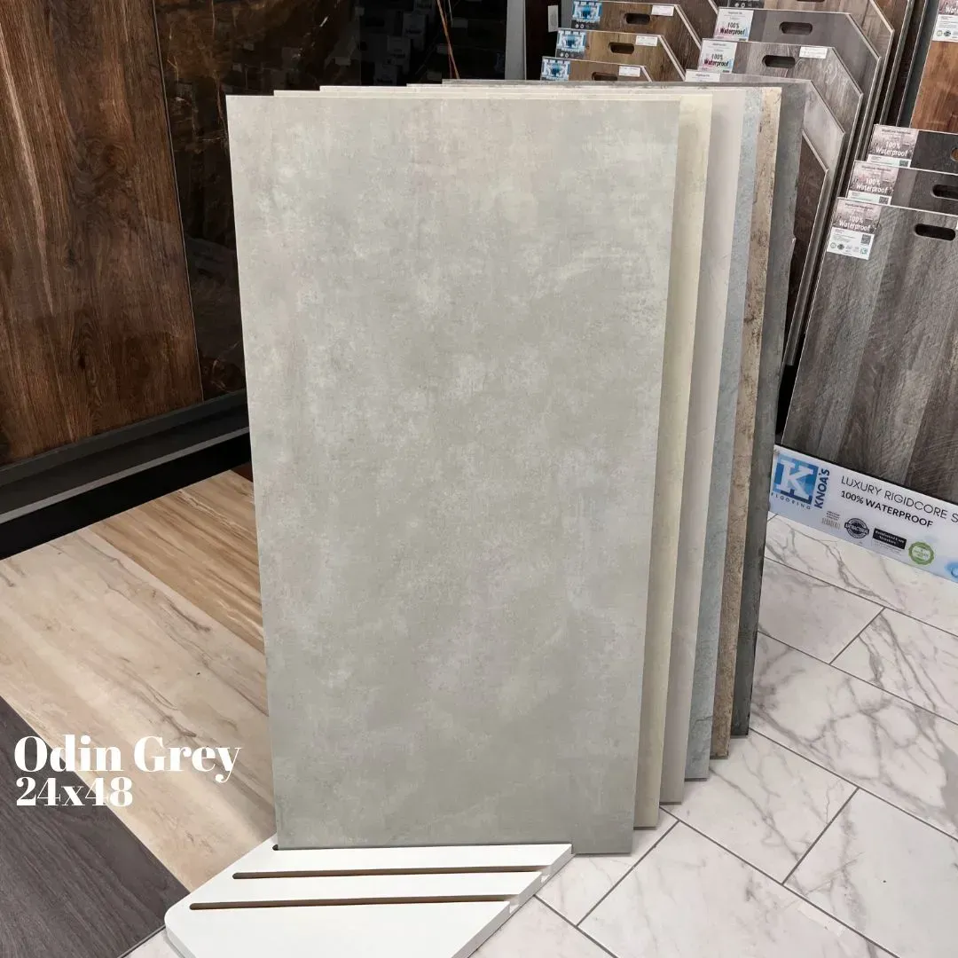 A display rack showing samples of rectangular Odin Grey 24x48 floor tiles in a showroom.