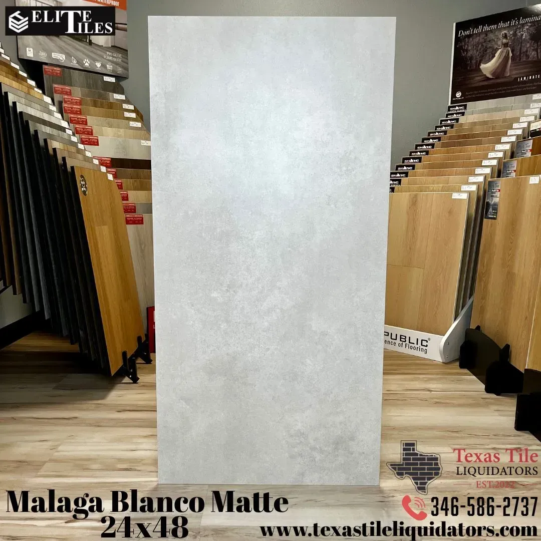 A large Malaga Blanco Matte 24x48 inch tile displayed in a showroom with wooden flooring samples in the background.