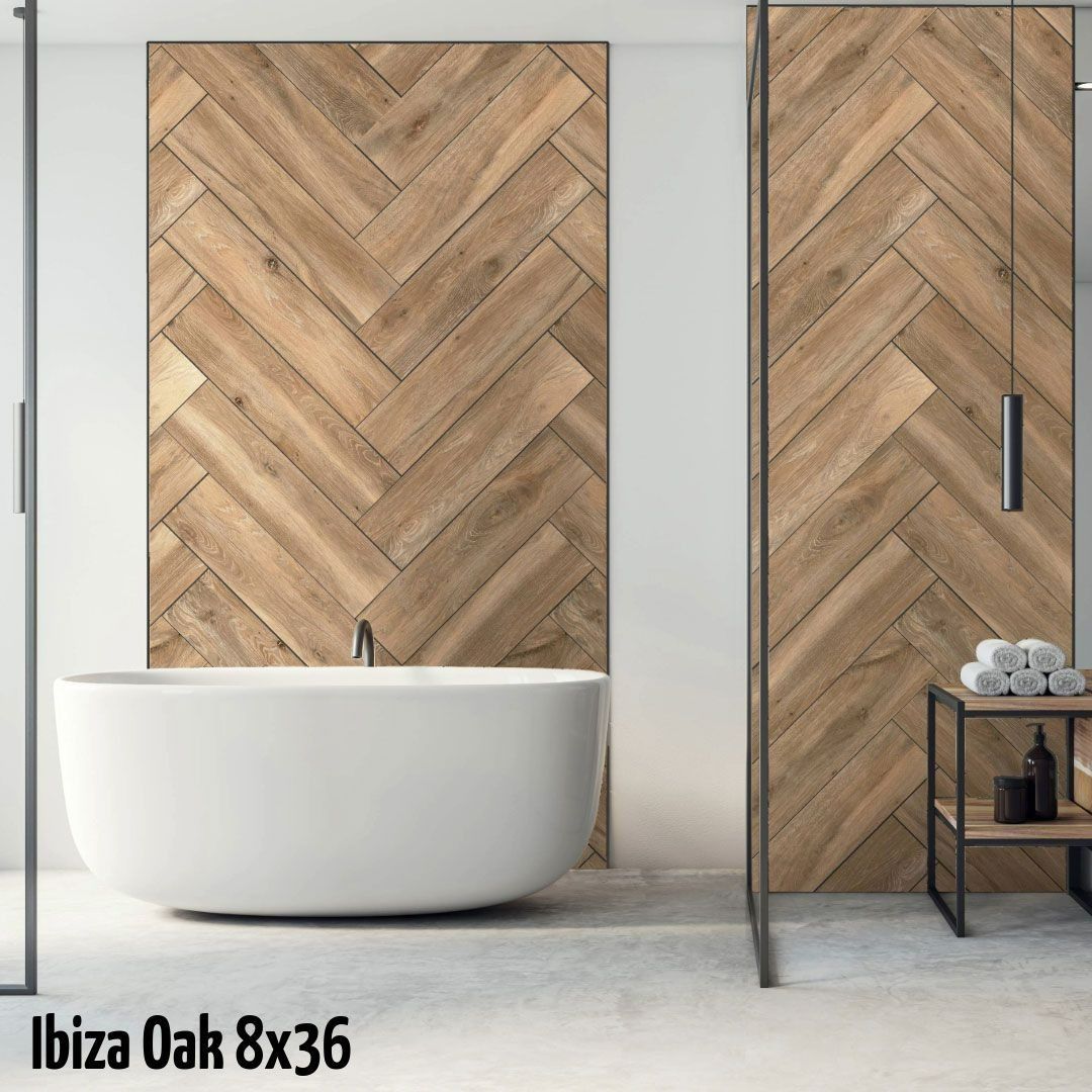A modern bathroom featuring a white freestanding tub against a wall with herringbone-patterned oak wood tiles.
