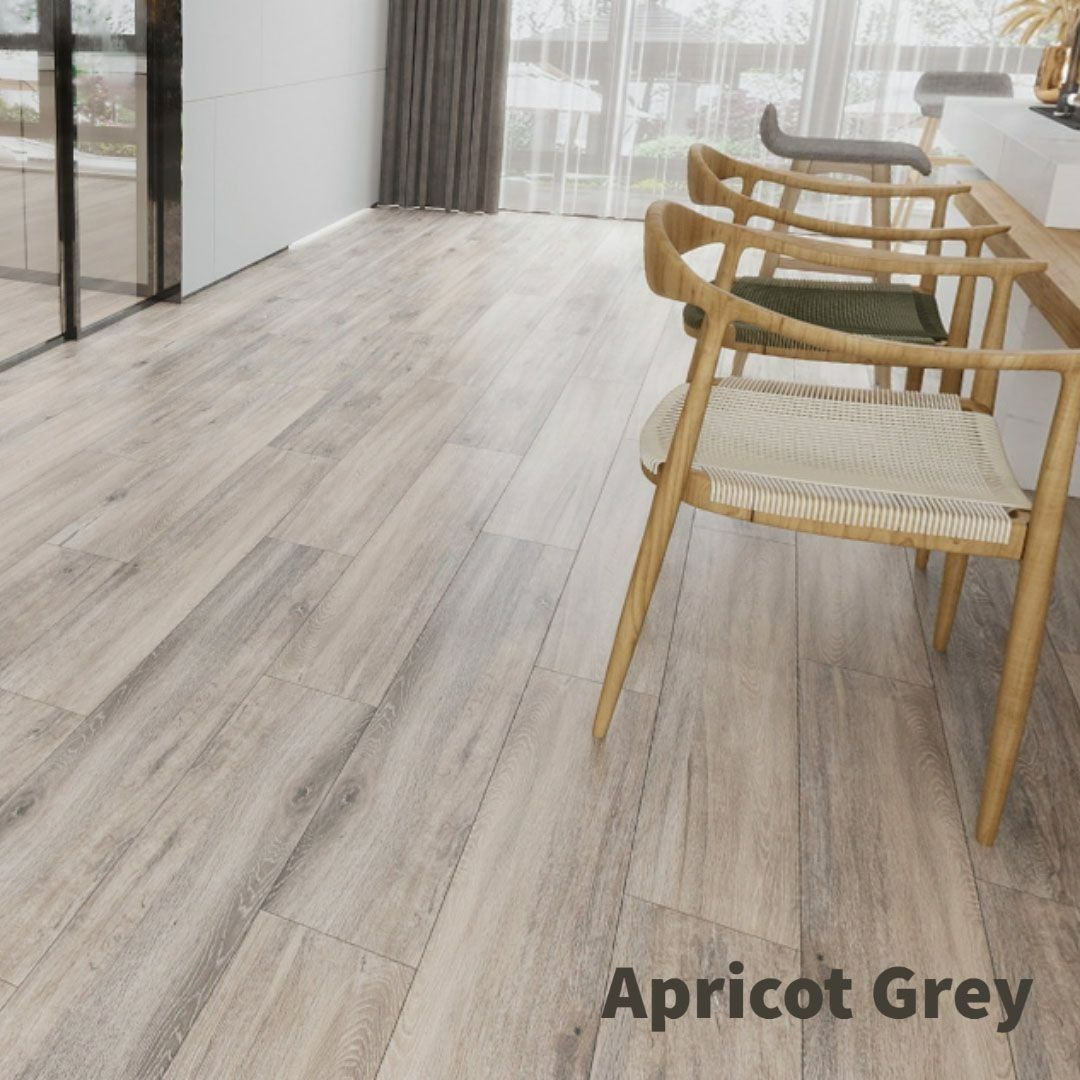 Apricot Grey wood-look flooring planks in a bright, modern room featuring a row of wooden chairs along a counter.
