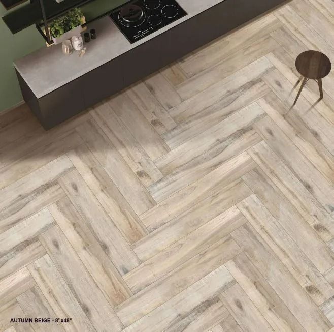 Herringbone-patterned beige wood-look tiles installed on a floor in a kitchen setting.