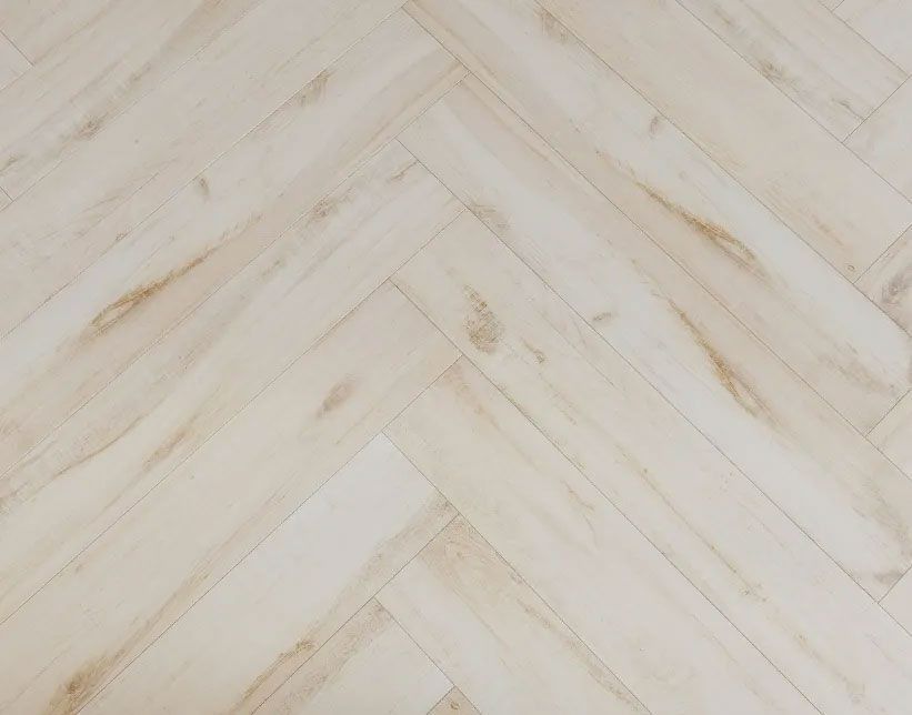 Light-toned wood planks arranged in a herringbone pattern with subtle brown grain textures.